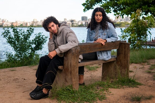 Sad couple sitting on the bench by the lake