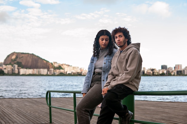 Foto gratuita coppia triste seduta vicino al molo vicino al lago