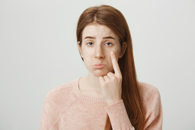 Sad and cute redhead girl showing teardrop