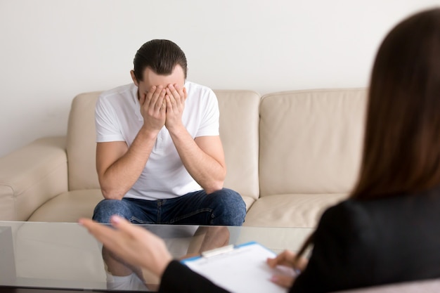 Sad depressed man at the psychologist, feeling hopeless and desperate