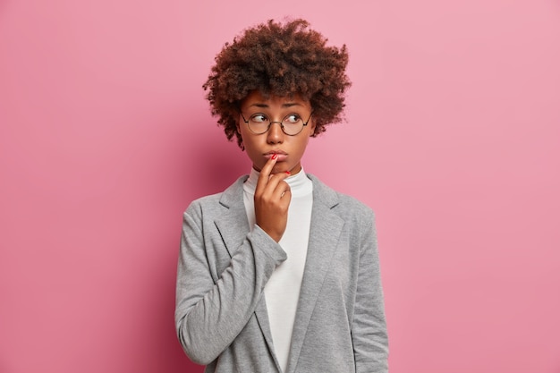 Free photo sad discontent curly woman executive worker looks unhappily aside, purses lips, expresses regret, has problem, needs good advice, dressed formally