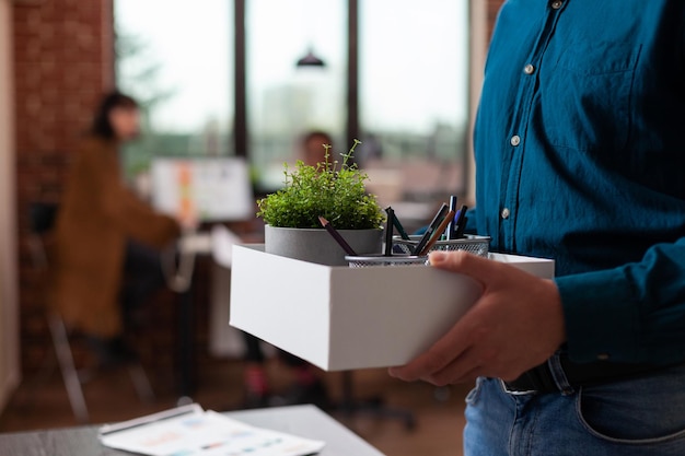 Triste uomo imprenditore licenziato che tiene una scatola con roba dopo essere stato licenziato mentre i suoi colleghi guardavano casa che lavorava nell'ufficio di avvio. gli uomini d'affari fanno brainstorming sulle idee per lo sviluppo di progetti di marketing