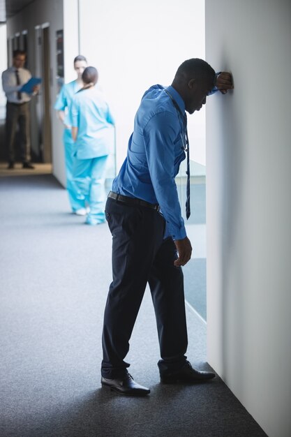 Sad doctor leaning on wall