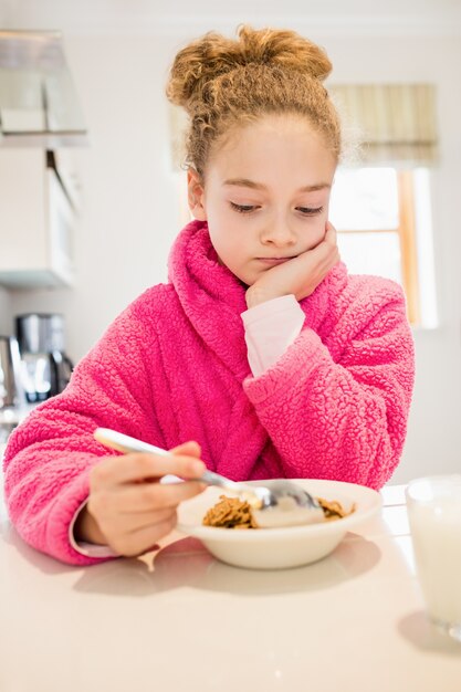 Sad girl having breakfast in kitchen