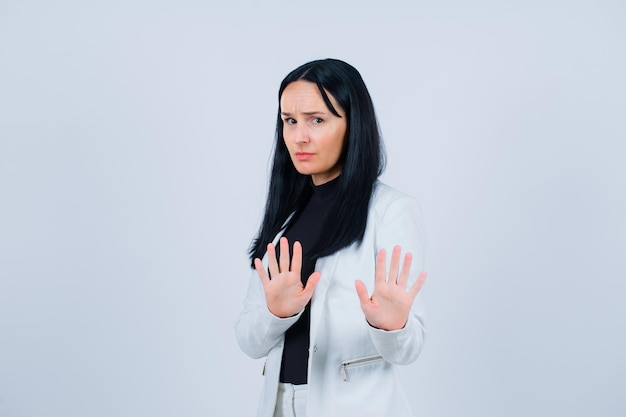 Sad girl is showing stop gesture with hands on white background