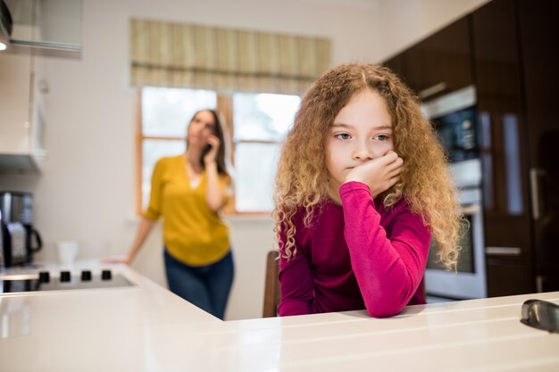 Sad girl sitting in kitchen