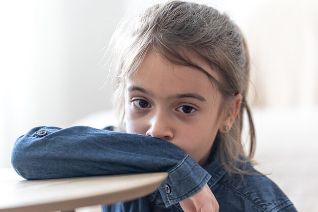 Sad girl sitting at the table at school, back to school concept.