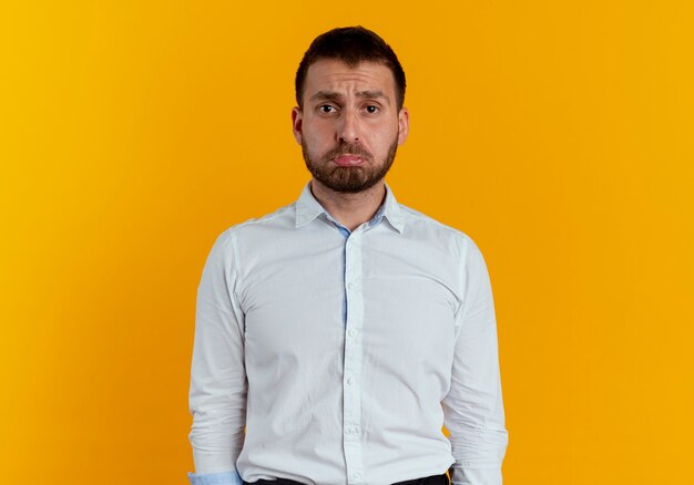 Sad handsome man looking isolated on orange wall