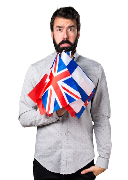 Free photo sad handsome man with beard holding many flags