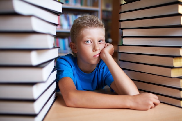 Sad kid surrounded by books