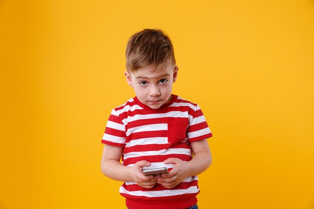 Sad little boy holding mobile phone