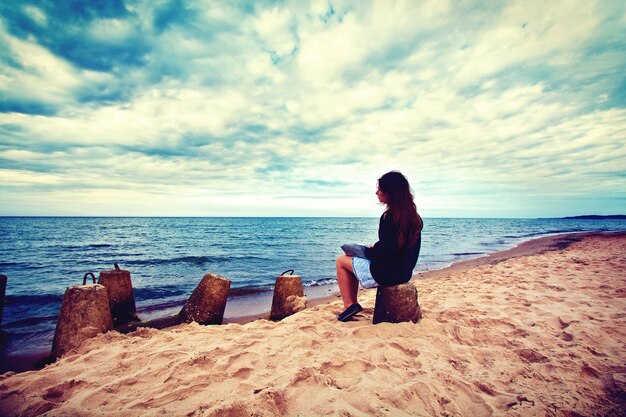 Sad, lonely woman sitting on the beach.