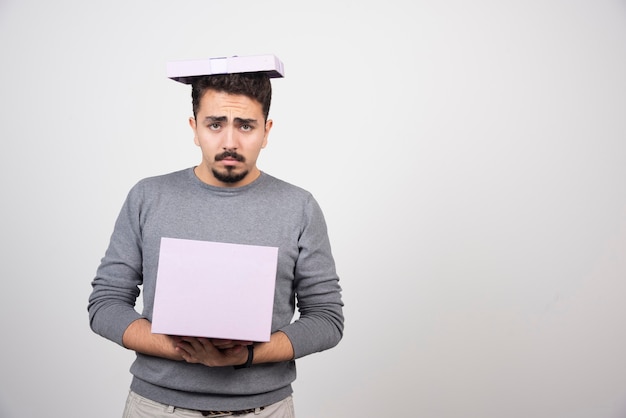 Sad man holding in hands a purple box .