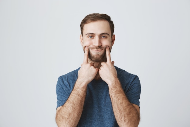 Sad man pull smile with fingers