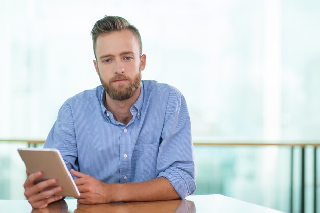 Sad Man Sitting at Cafe Table and Using Tablet