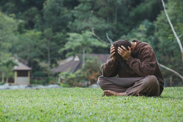 Sad man sitting on green grass