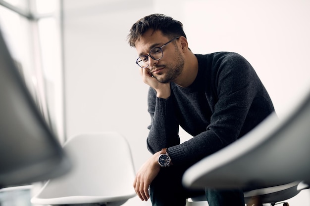 Sad man thinking of something while waiting a group therapy to start