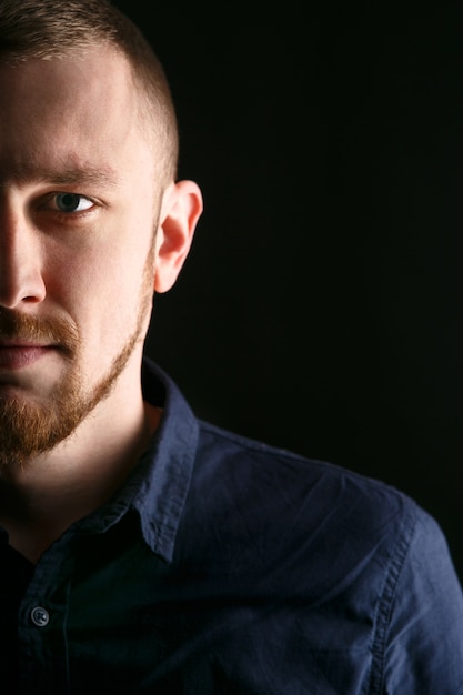 Sad man with red beard on black background 