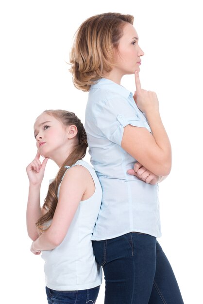 悲しい母と娘が問題を抱えているか、白で隔離されたスタジオを背中合わせに立っている喧嘩