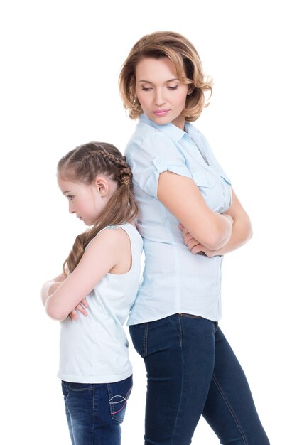 Sad mother and daughter having problem or quarrel standing back to back studio isolated on white