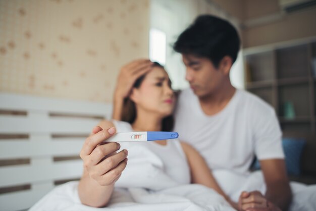 침대에 앉아 임신 테스트를 들고 불평 슬픈 부모