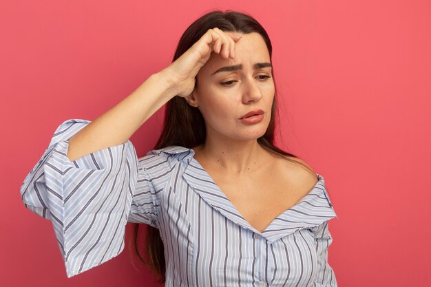 Sad pretty caucasian woman  hand on forehead on pink