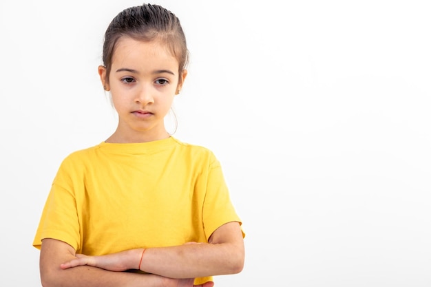 Free photo sad school girl dressed yellow tshirt arms folded on white background