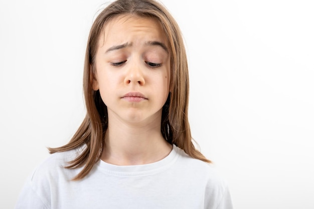 Foto gratuita ragazza adolescente triste che guarda in basso su uno sfondo bianco