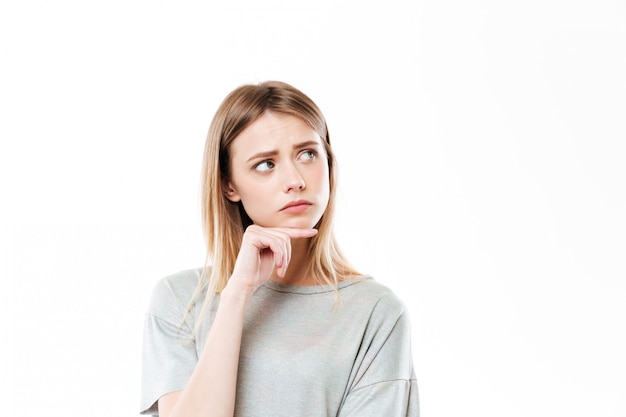 Sad thinking young woman standing isolated