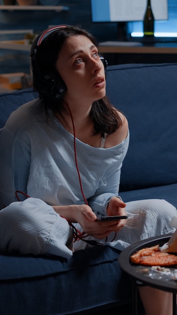 Sad thoughtful anxious woman listening music using smartphone feeling lonely worried concerned about...