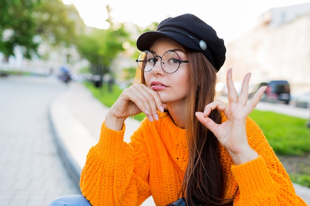 Sad woman showing ok , sitting on the street