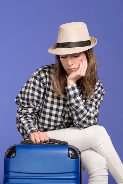 Free photo sad woman sitting on blue luggage