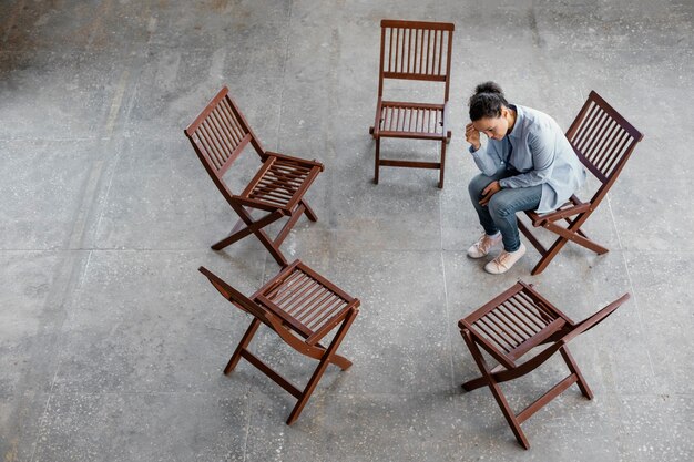 Sad woman sitting on chair full shot