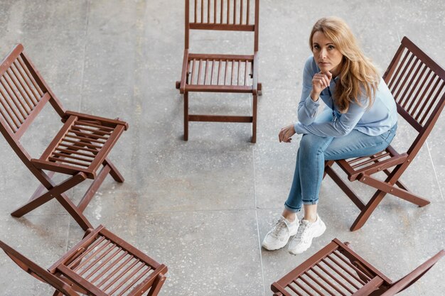 Sad woman sitting on chair full shot