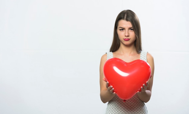 Triste donna in piedi con palloncino cuore rosso