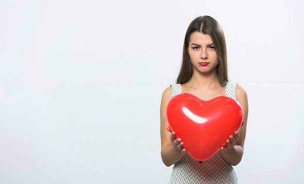 Sad woman standing with red heart balloon