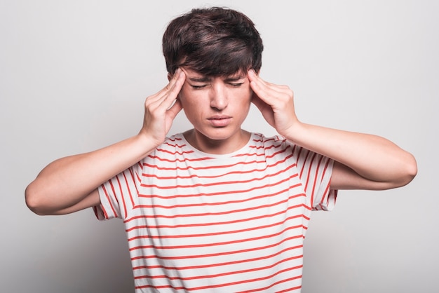 Sad woman suffering from headache touching her head against white background