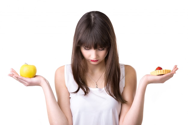 Sad woman with an apple in one hand and cake in the other