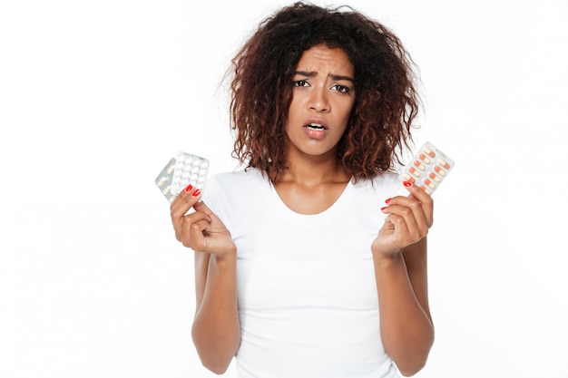 Free photo sad young african lady holding pills.