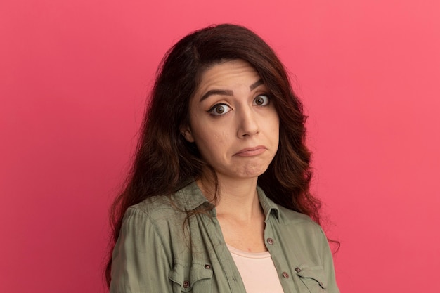 Sad  young beautiful girl wearing olive green t-shirt isolated on pink wall