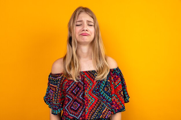 Sad young blonde slavic girl standing with closed eyes 