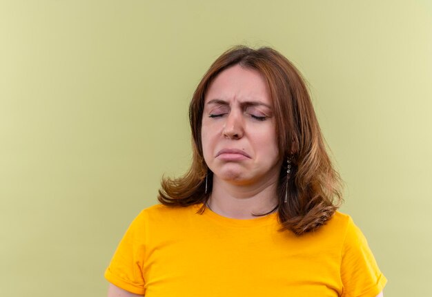 Sad young casual woman with closed eyes on isolated green space with copy space