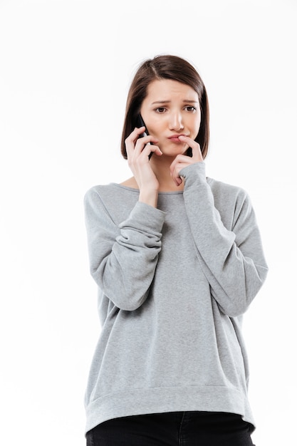 Унылая молодая кавказская женщина говоря по телефону.