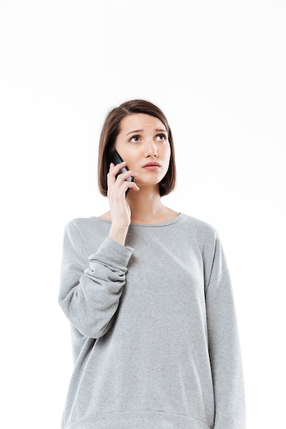 Sad young caucasian woman talking by phone.