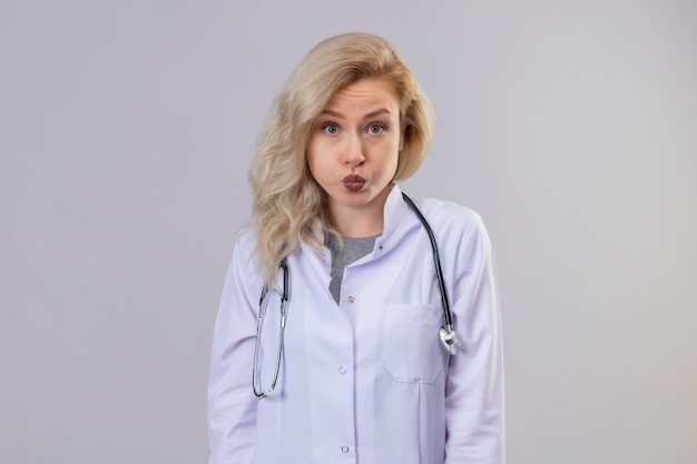 Free photo sad young doctor wearing stethoscope in medical gown on white wall