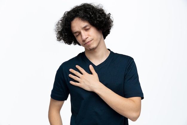 Sad young handsome man doing sorry gesture with closed eyes isolated on white background