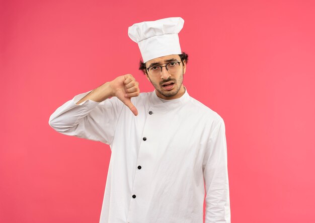 요리사 유니폼을 입고 슬픈 젊은 남성 요리사와 그의 엄지 손가락을 아래로 안경