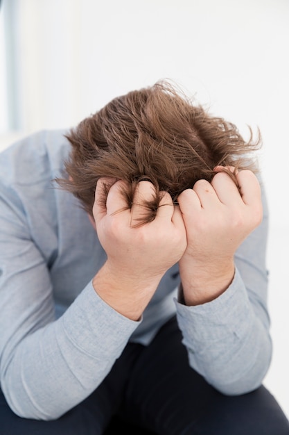 Free photo sad young man covering his face