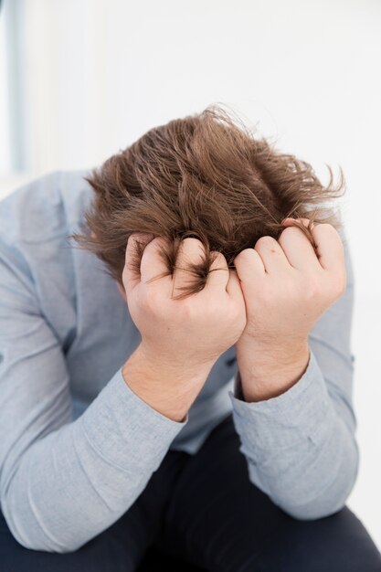 Sad young man covering his face