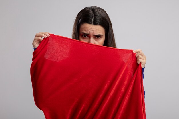 Sad young superhero girl covered face with cloak isolated on white